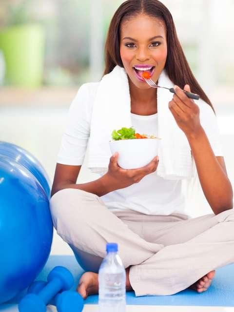 Woman on exercise mat eating fruit